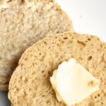 Sliced English muffins with butter on top.