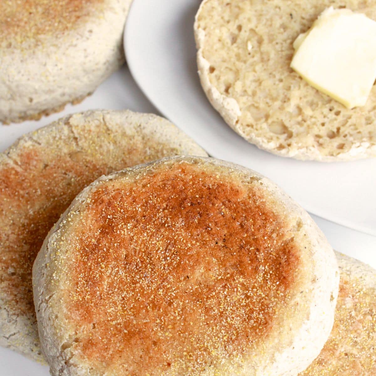 Sliced gluten-free English muffin topped with butter.