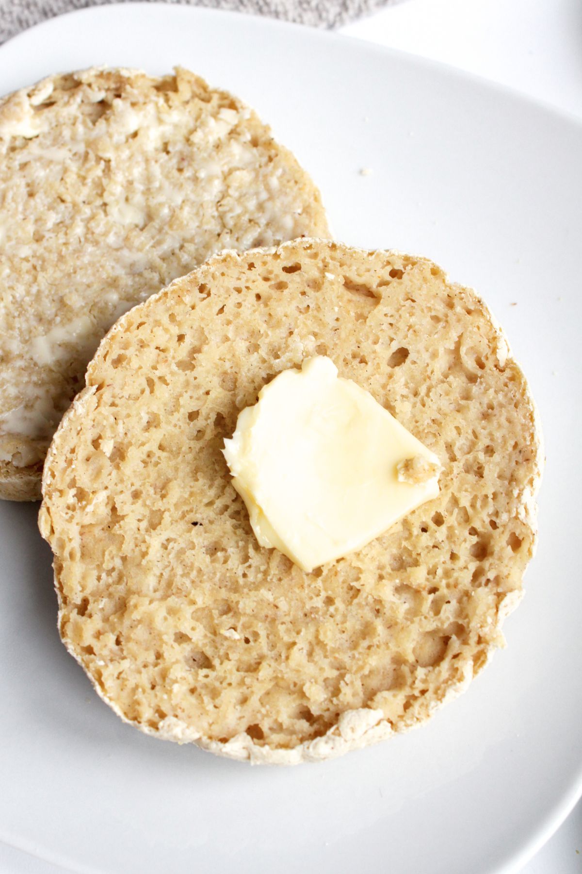 Half-sliced English muffin with a slab of butter on top.