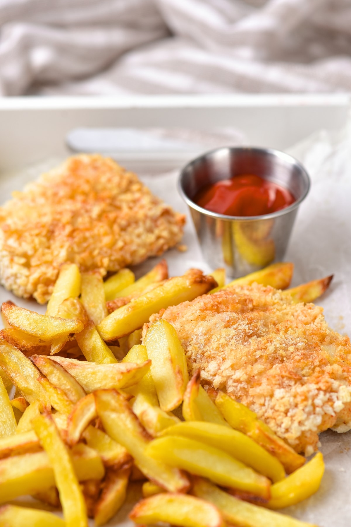 View of fried fish and fries on parchment-lined tray.