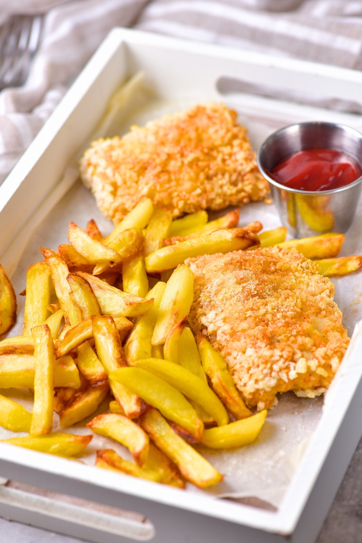 Air fryer fish and chips on parchment-lined tray.