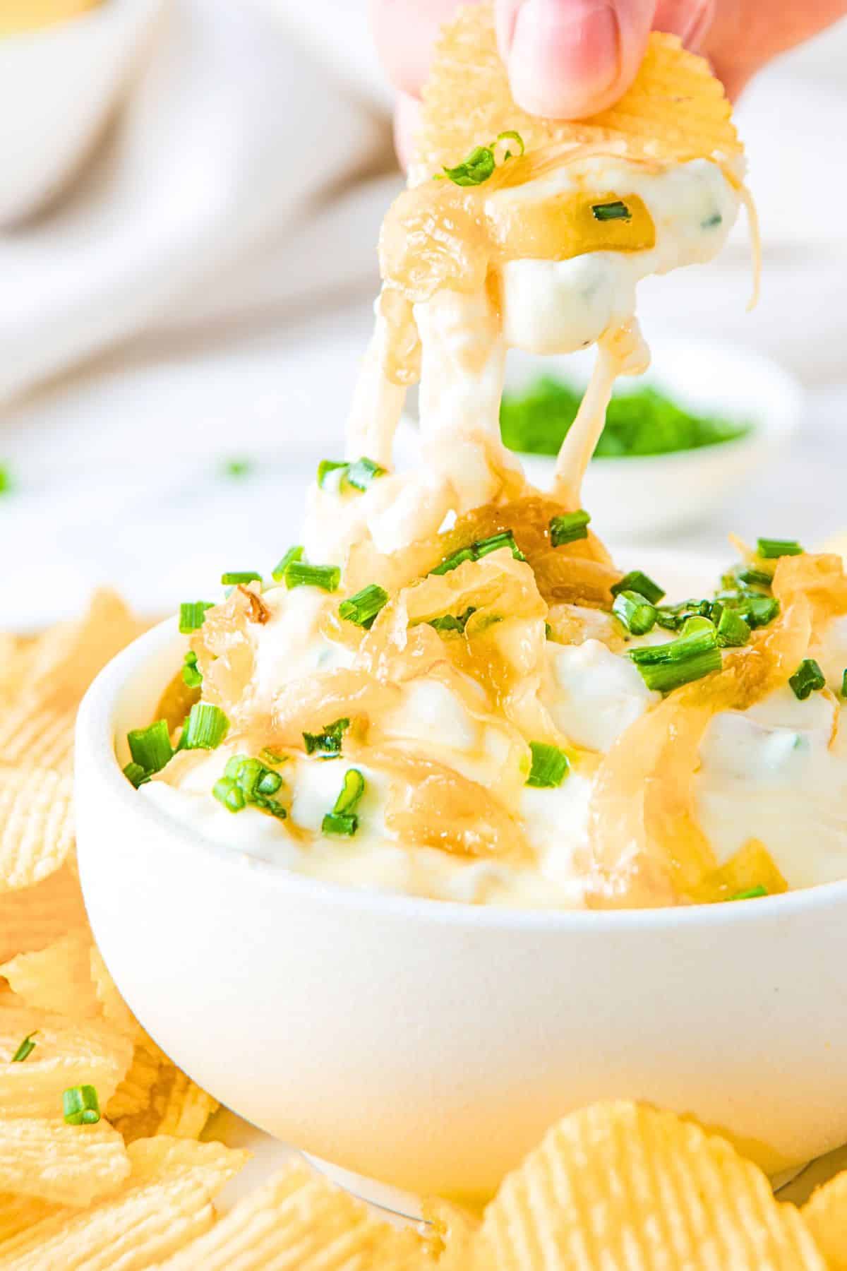 Dipping a chip into a bowl of caramelized onion dip.