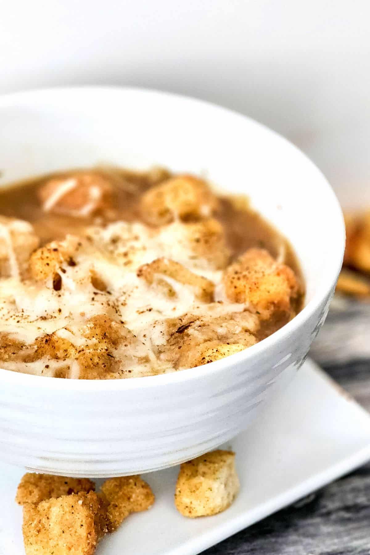 A bowl of gluten-free French onion soup topped with croutons and cheese.