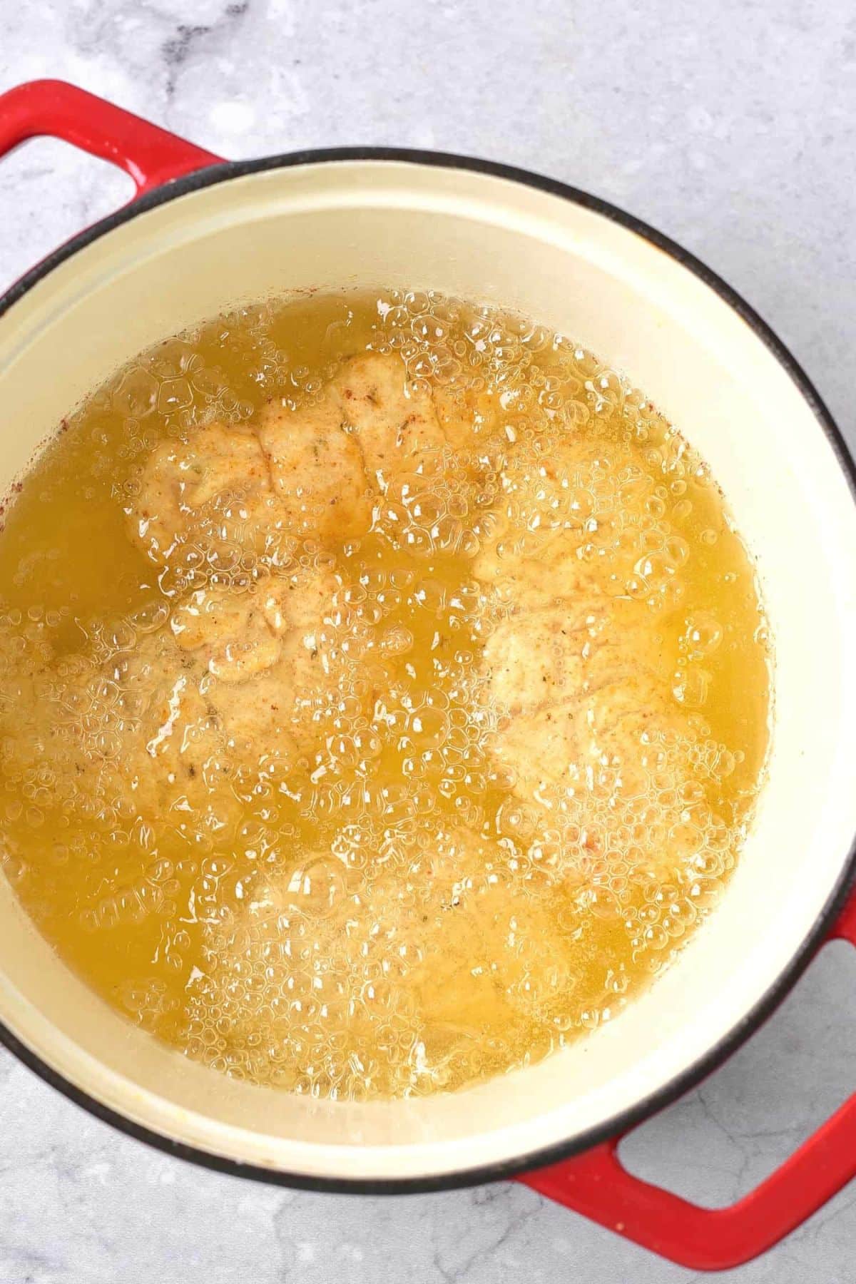 Deep frying chicken in a large pot of oil.