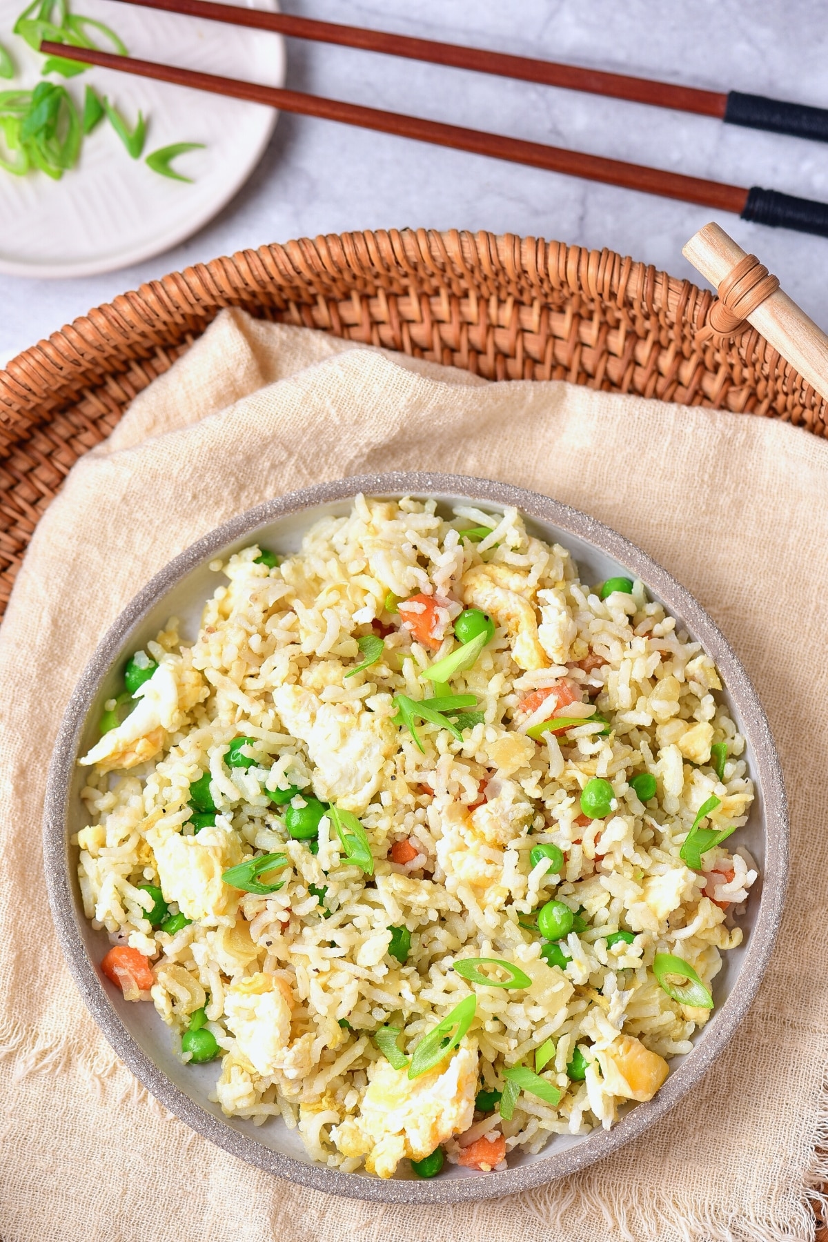 Top down view of a bowl of gf fried rice on a kitchen towel in a wicker basket.