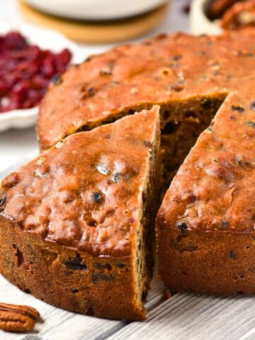 A half-sliced fruit cake on wooden board