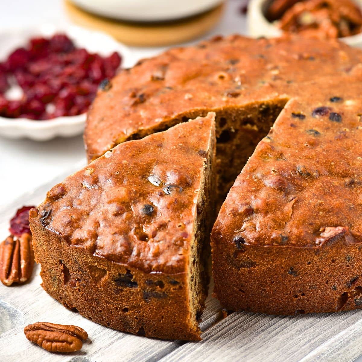 A half-sliced fruit cake on wooden board