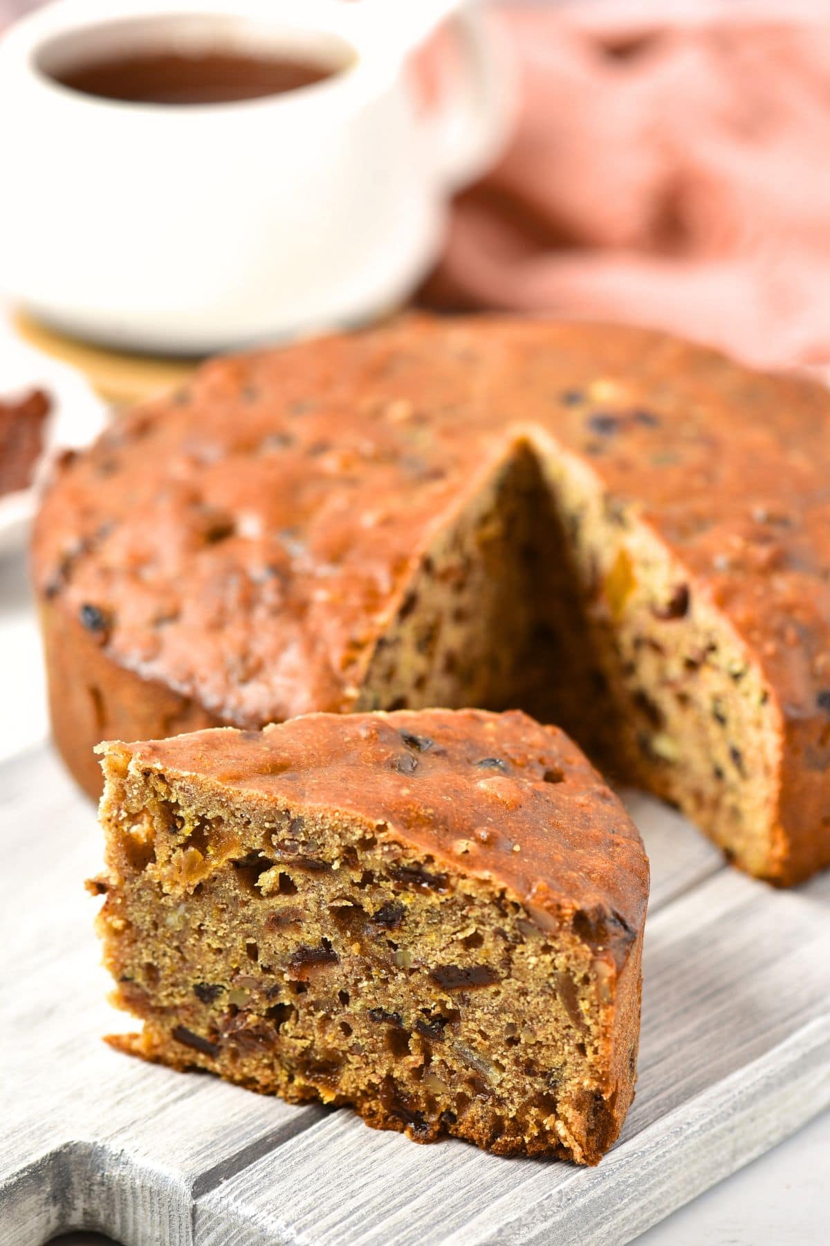 Up close view of a slice of gluten-free fruit cake on grey board.