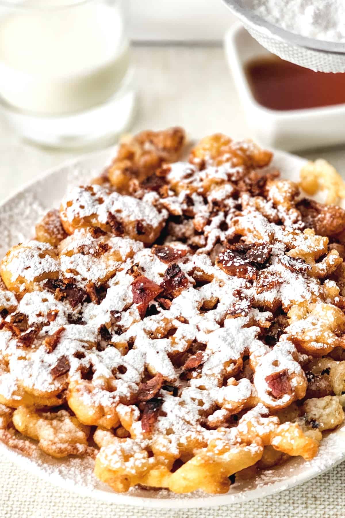 A plate of funnel cakes with powdered sugar sprinkled on top.