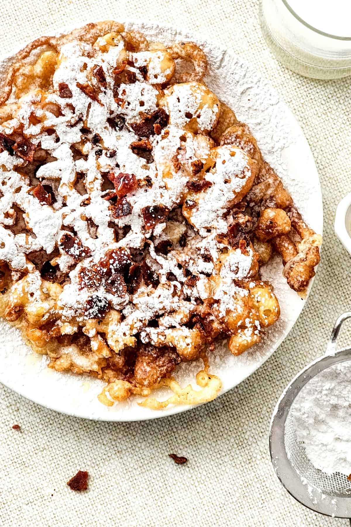 Top down view of funnel cake sprinkled with powdered sugar.