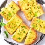 Sliced garlic bread on a parchment-lined plate.