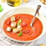 A bowl of gazpacho soup topped with basil leaves and croutons