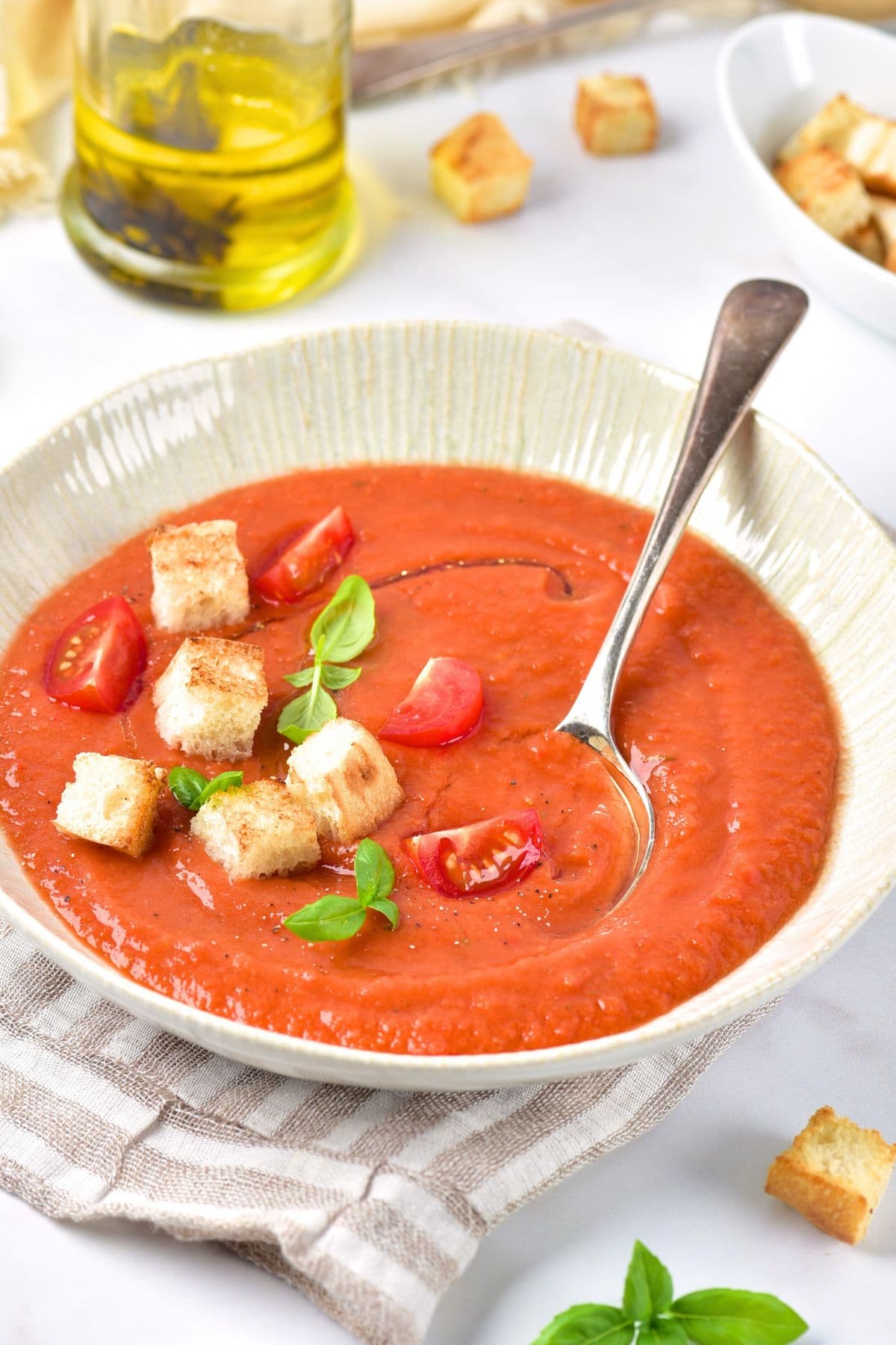A spoon in a bowl of gazpacho topped with garnishes