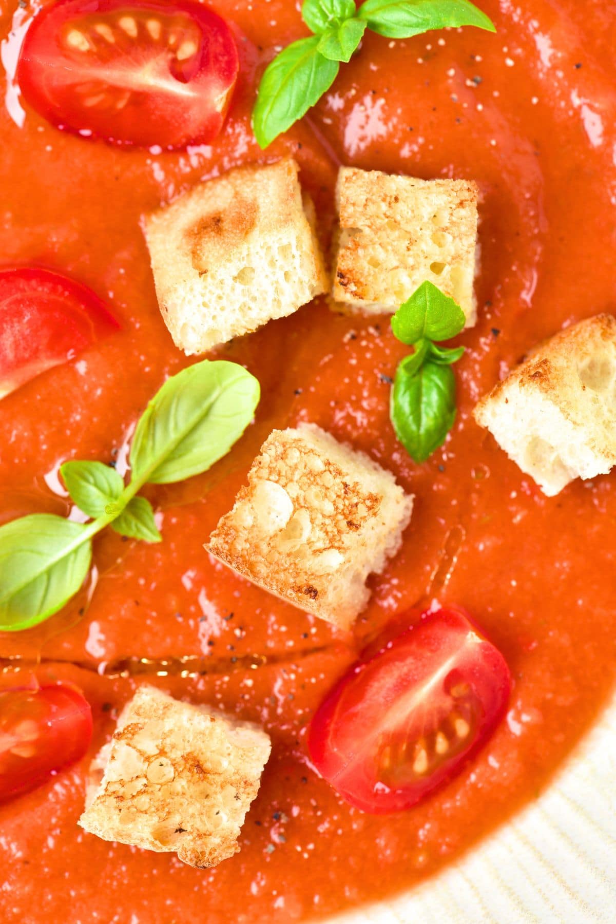 A bowl of gluten-free gazpacho topped with basil, tomatoes and croutons.