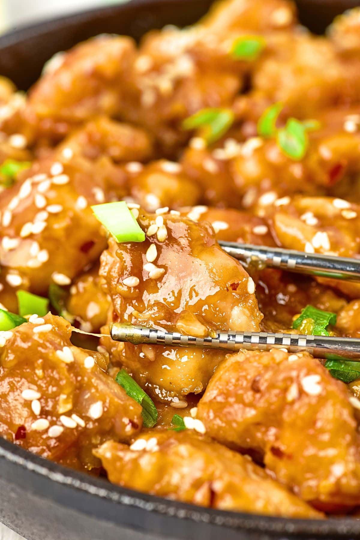 Chopsticks picking up chicken pieces in skillet