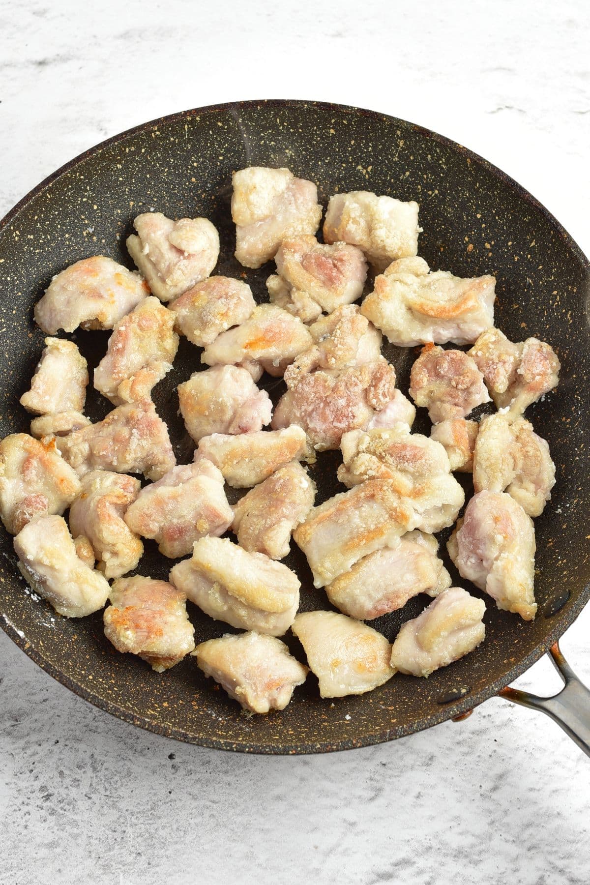 Pan-frying cornstarch coated chicken pieces in skillet