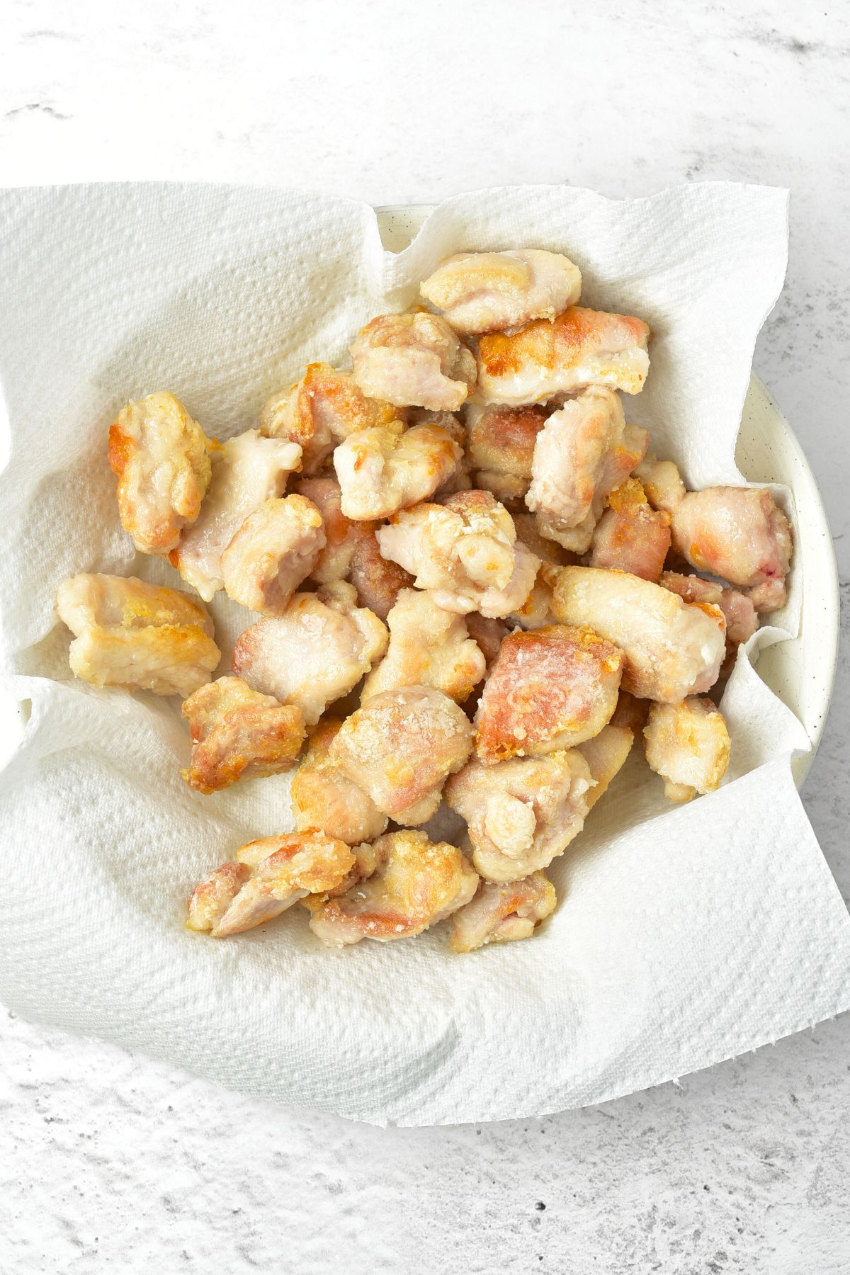 Pan-fried chicken pieces in paper towel lined bowl