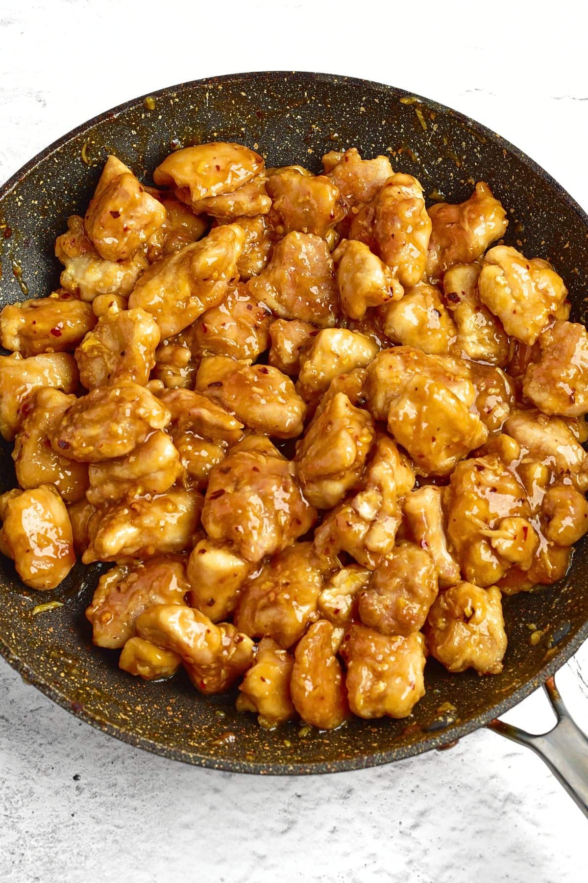 Chicken pieces coated in brown sauce in skillet
