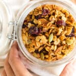 Hand holding a jar of gluten-free homemade granola.