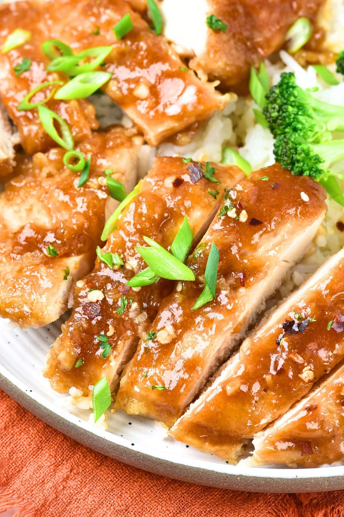 A plate of sliced honey garlic chicken topped with green onions