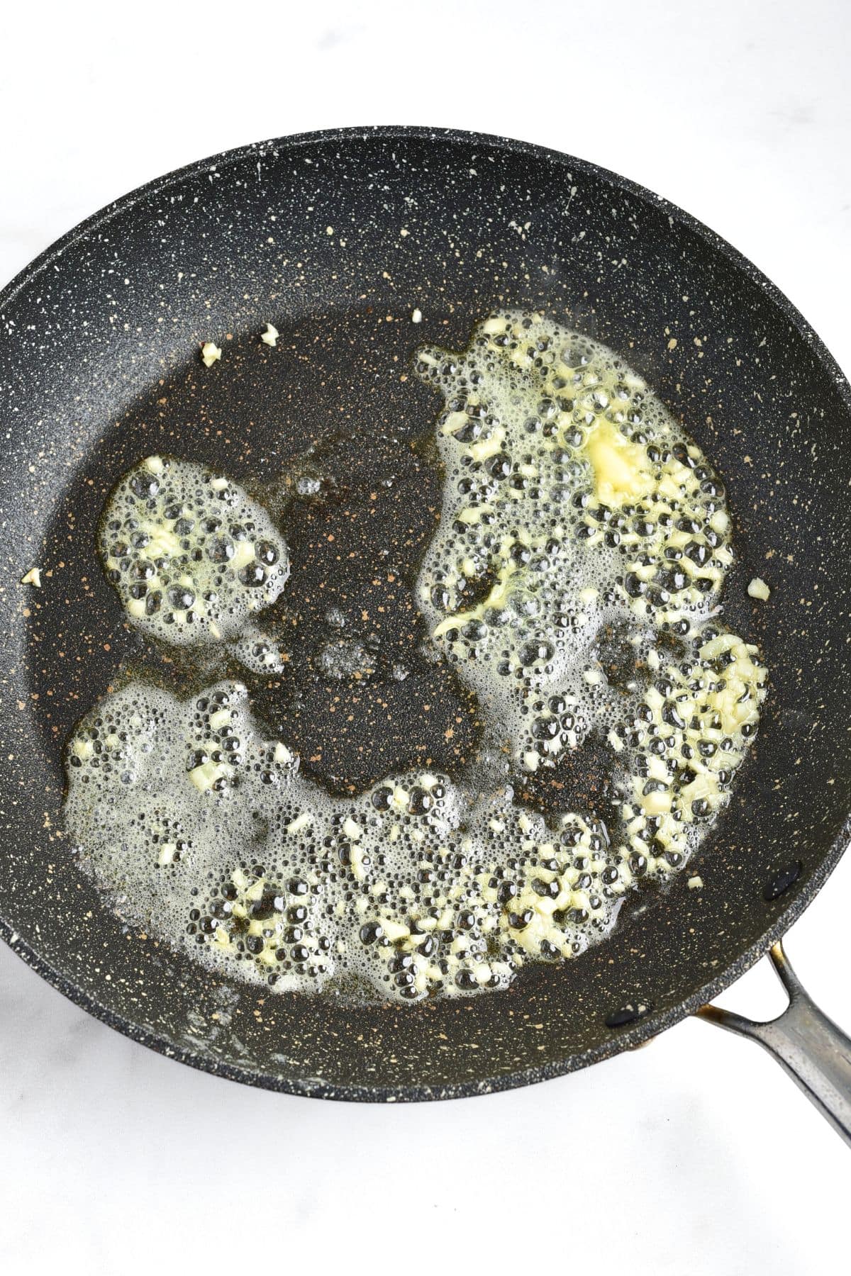 Sautéing minced garlic in skillet