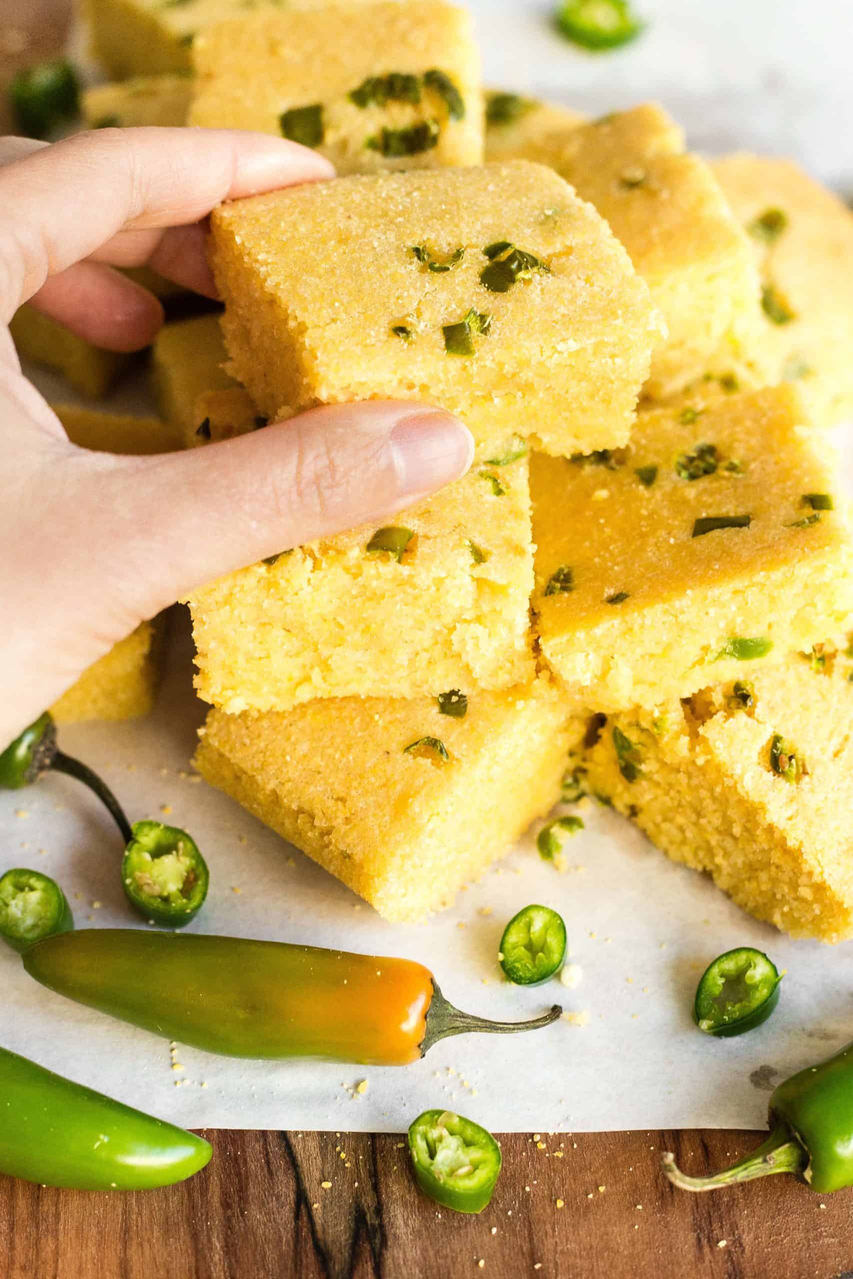 A hand picking up a piece of gluten-free jalapeño cornbread.