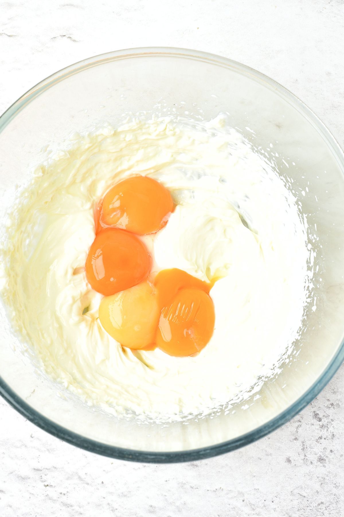 Egg yolks on top of cream cheese in a bowl