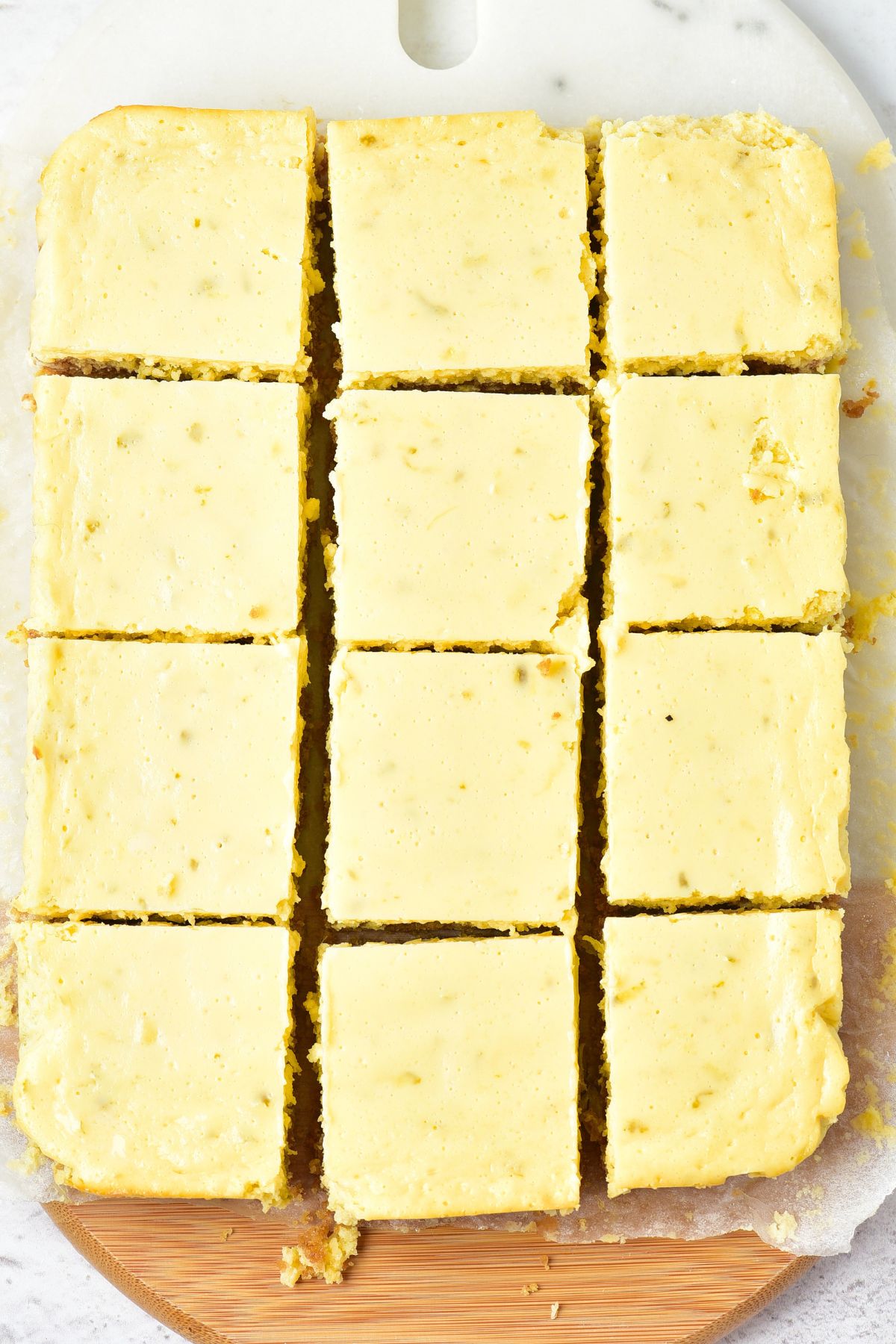 Squares of key lime bars on parchment-lined wooden board