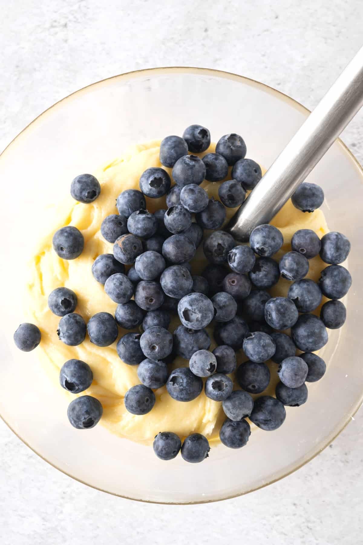 Fresh blueberries on top of cake batter in bowl.