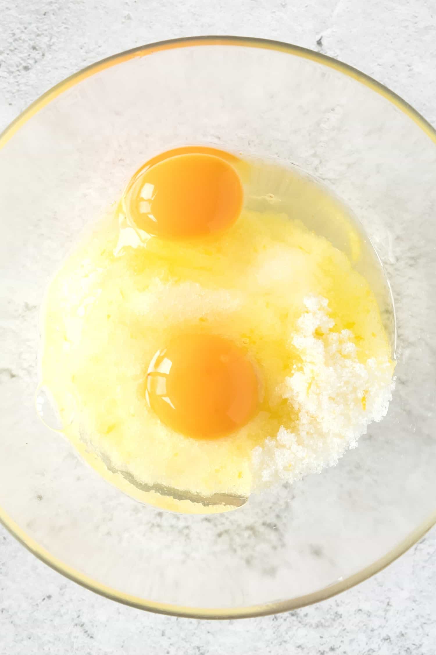 Sugar and eggs in a glass mixing bowl.