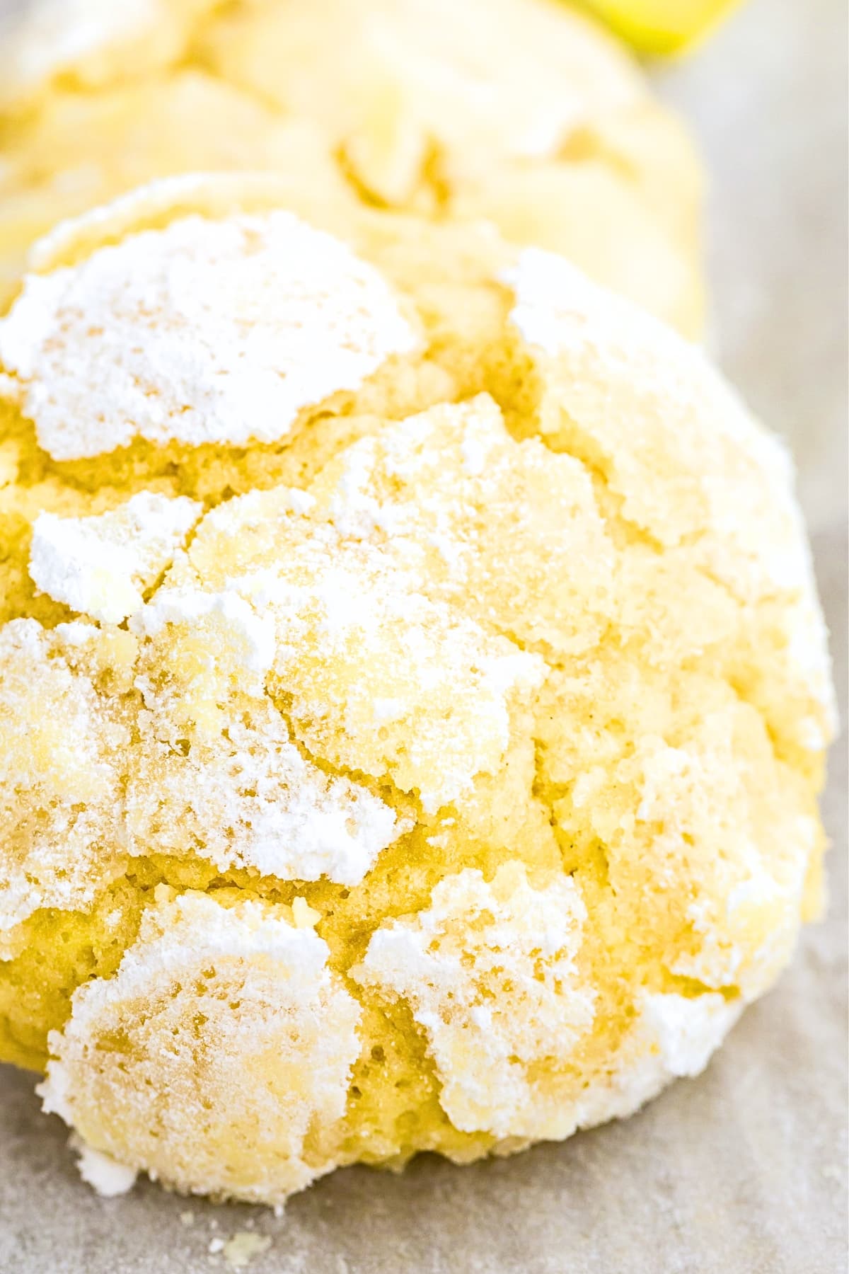 Up close shot of a lemon crinkle cookie on parchment paper.