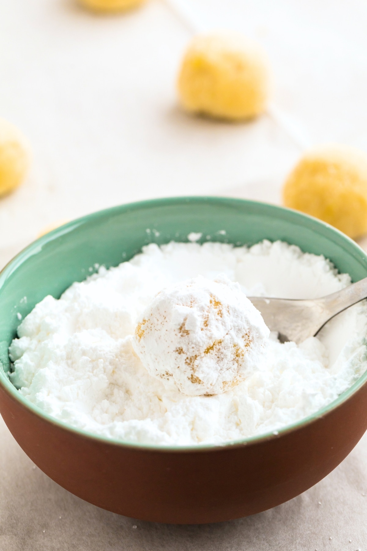 Rolling lemon cookie dough balls in powdered sugar.