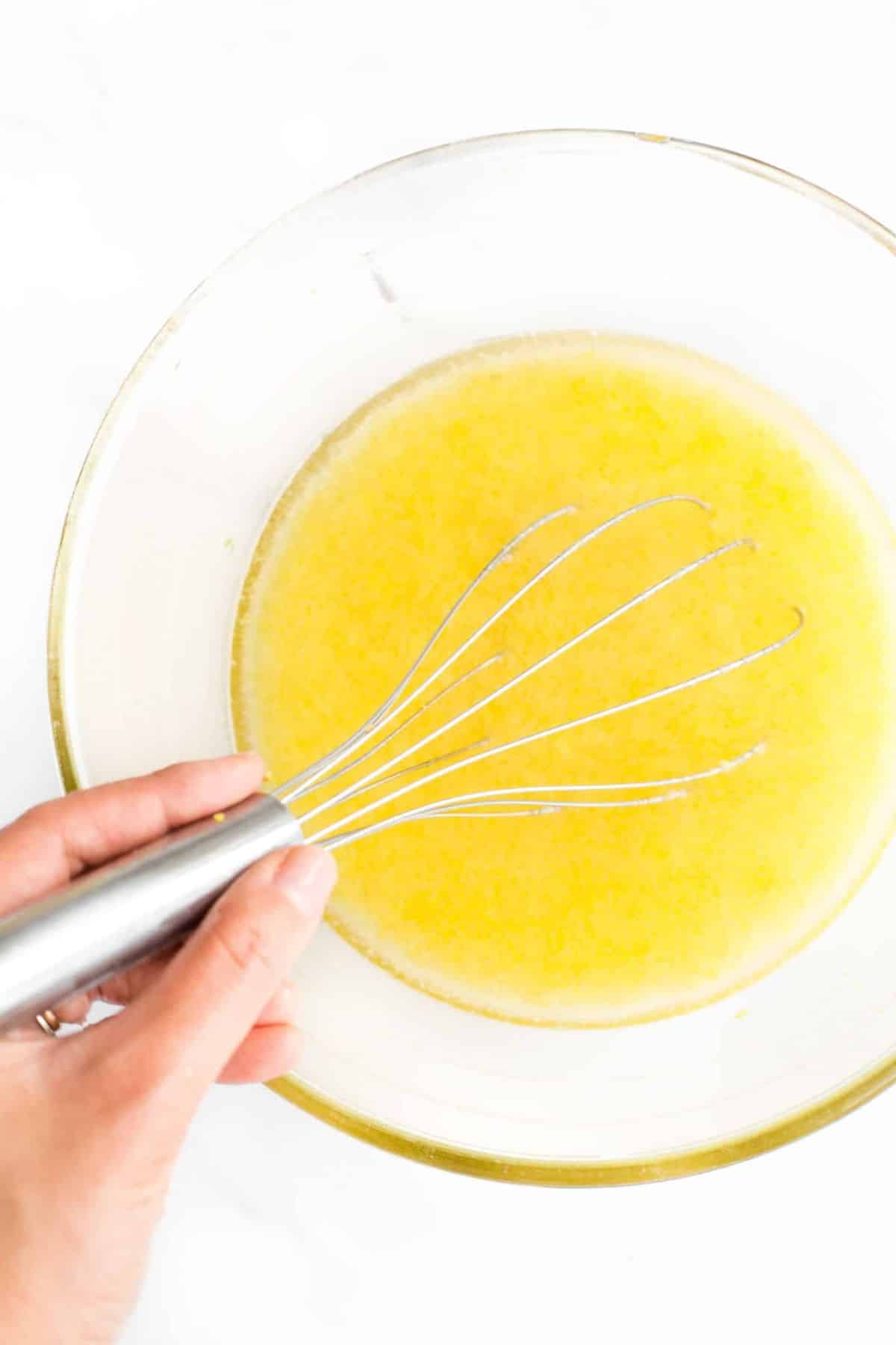 Whisking yellow liquid mixture with whisk.