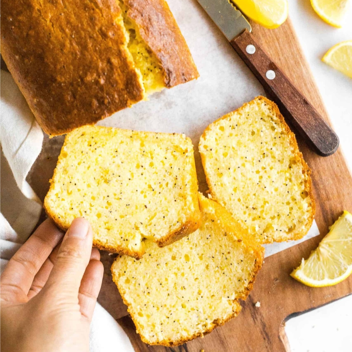 Slices of lemon poppyseed bread on wooden board.