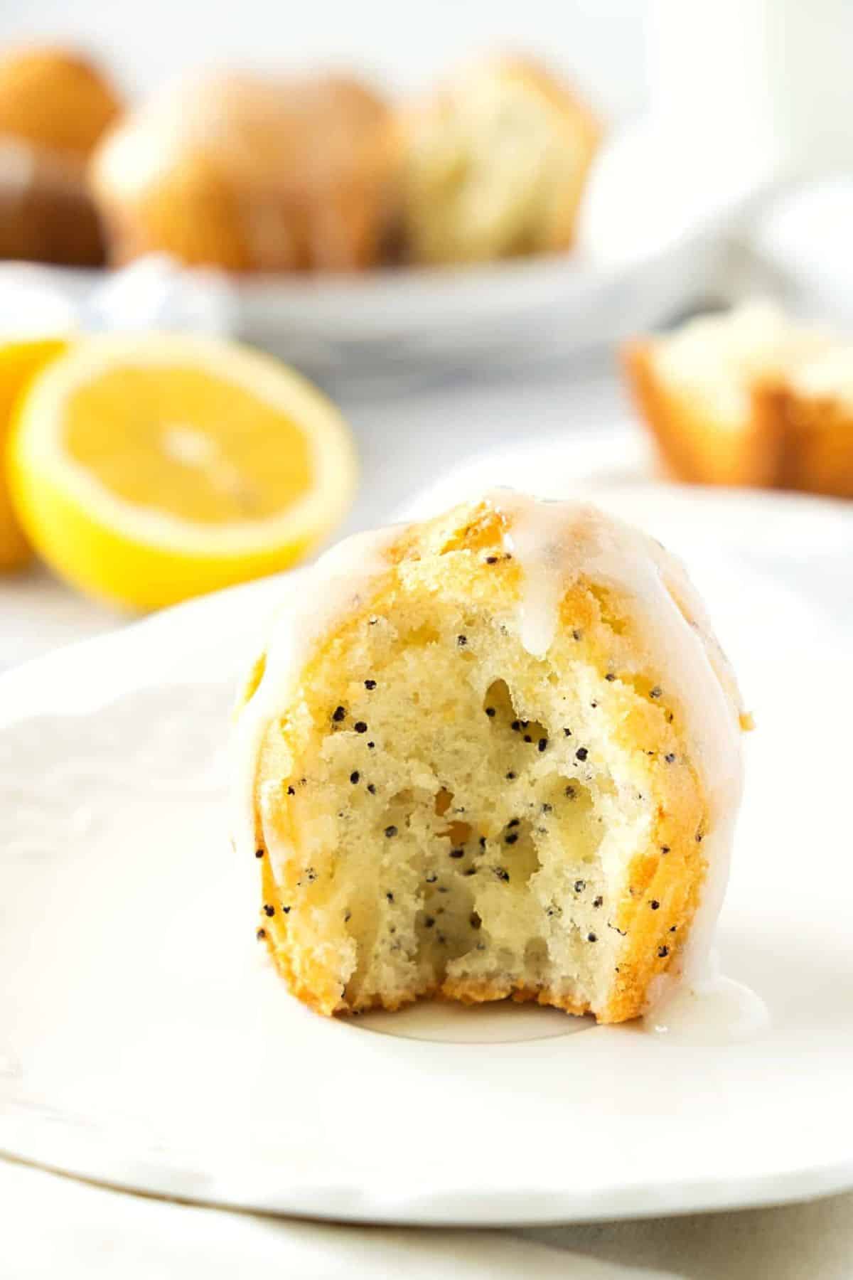 Up close shot of half-eaten lemon poppy seed muffin on plate.