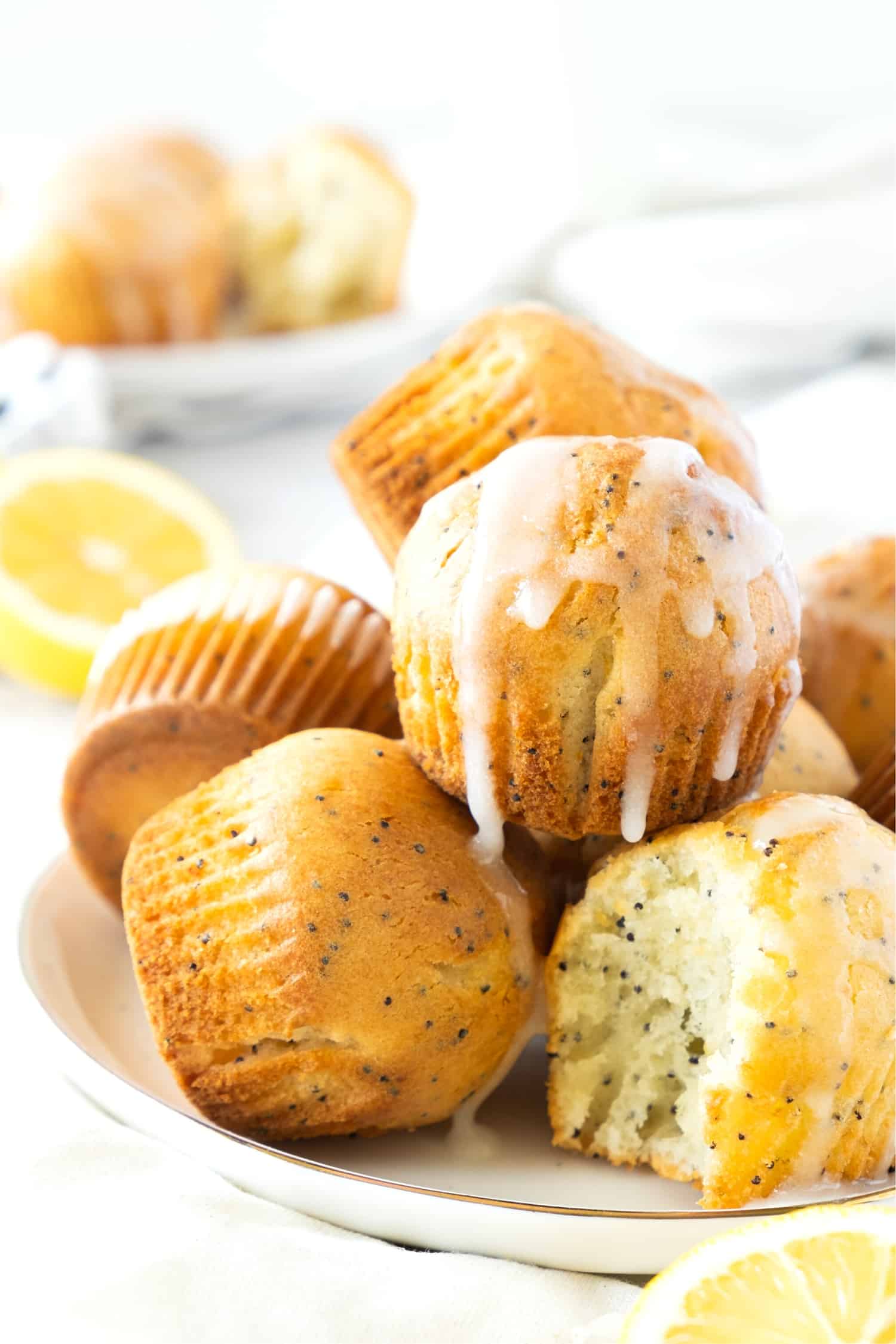 A plate full of gluten-free lemon poppy seed muffins drizzle in lemon glaze.