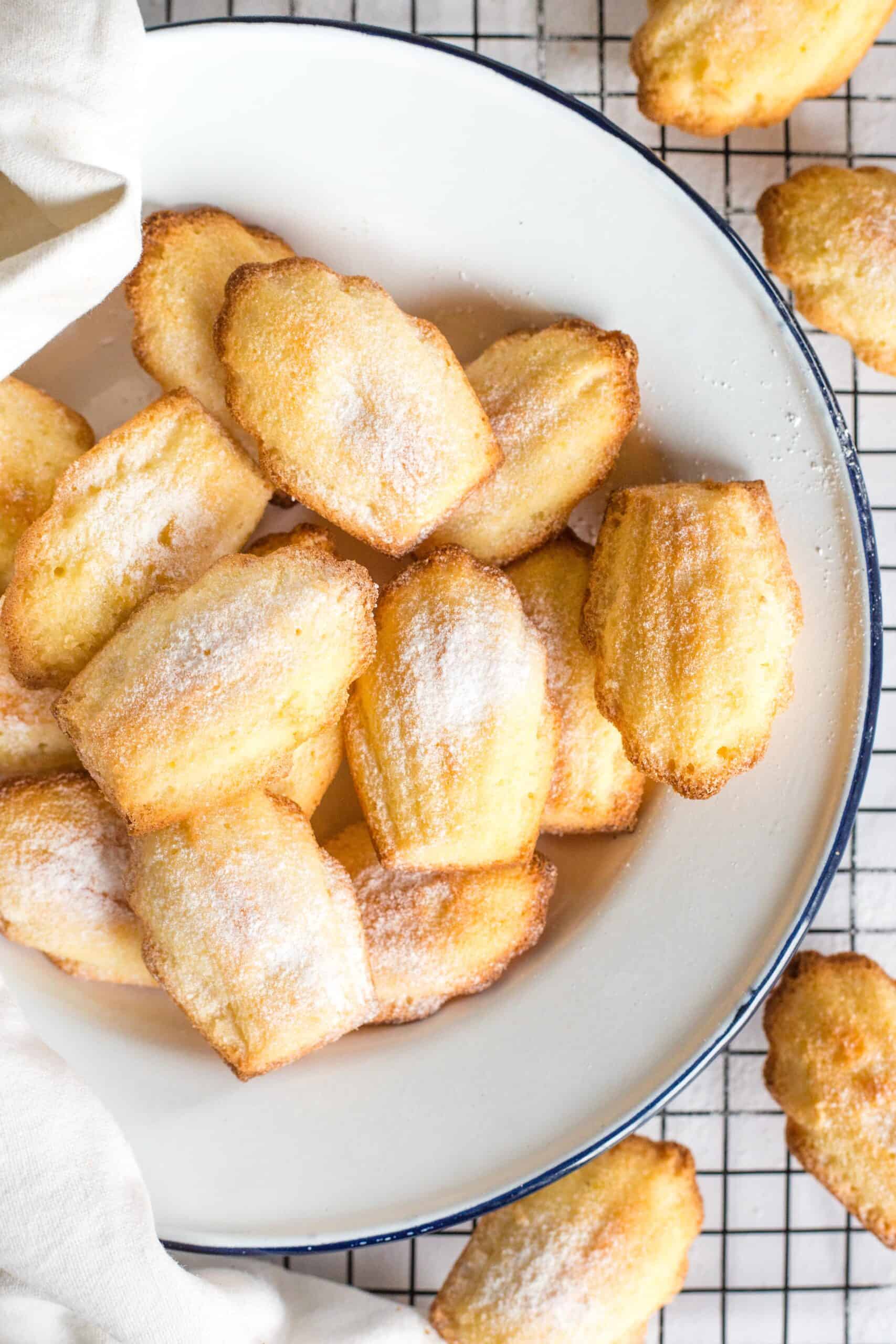 A plate full of gluten-free madeleines on a wire rack.