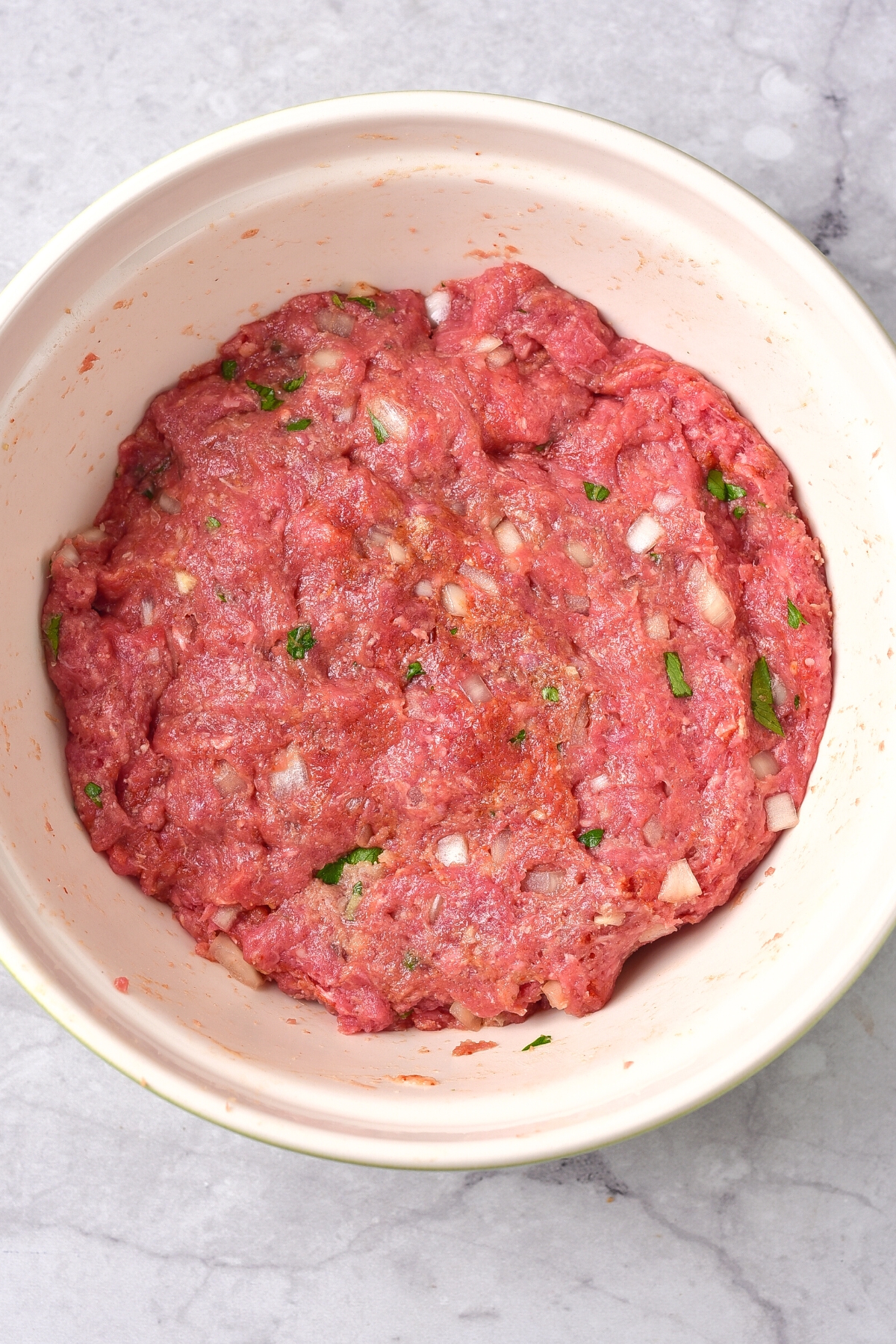Ground beef mixture in white mixing bowl.