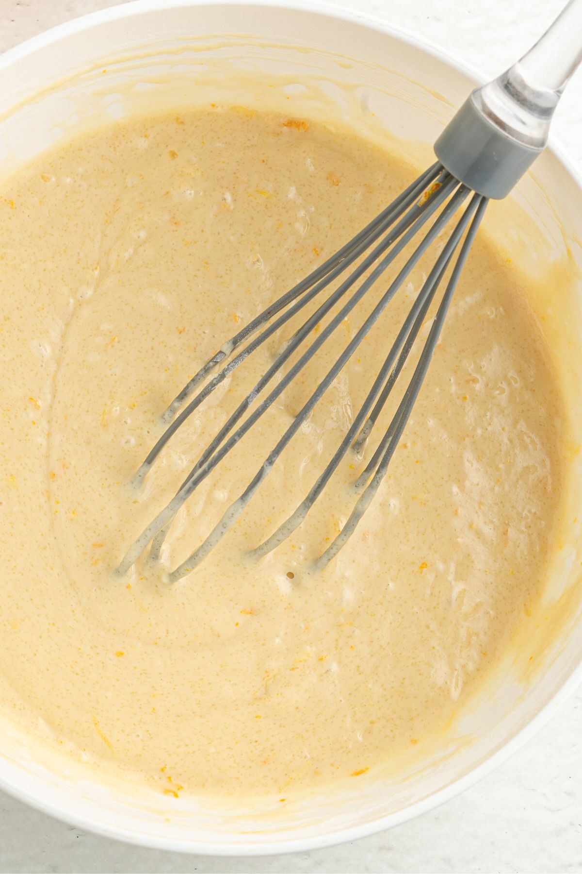 Whisking cake batter in white bowl.