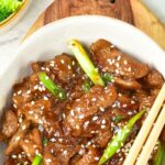 Top down view of bowl of beef slices and green onions