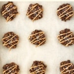 Top down view of peanut butter drizzled cookies on parchment.