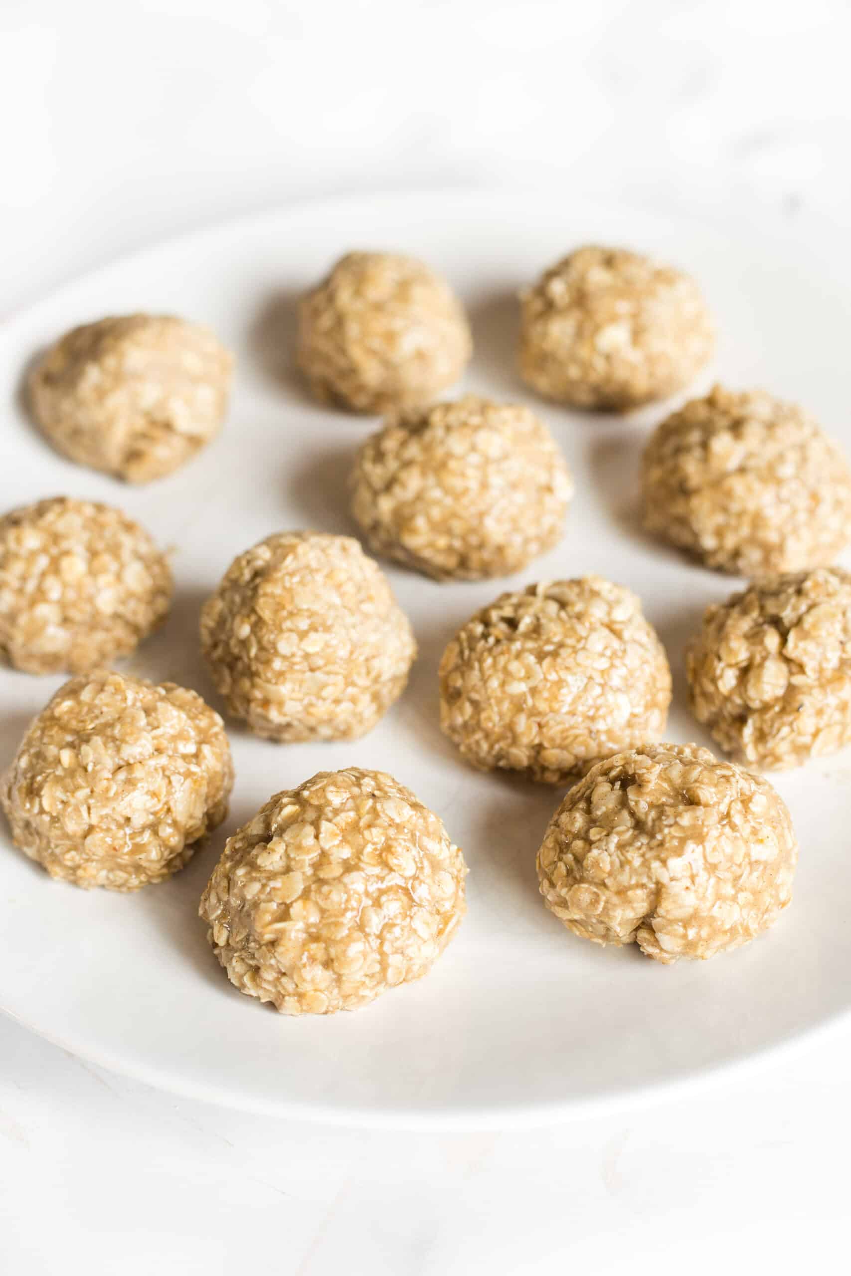 Balls of oatmeal cookie dough on a white plate.