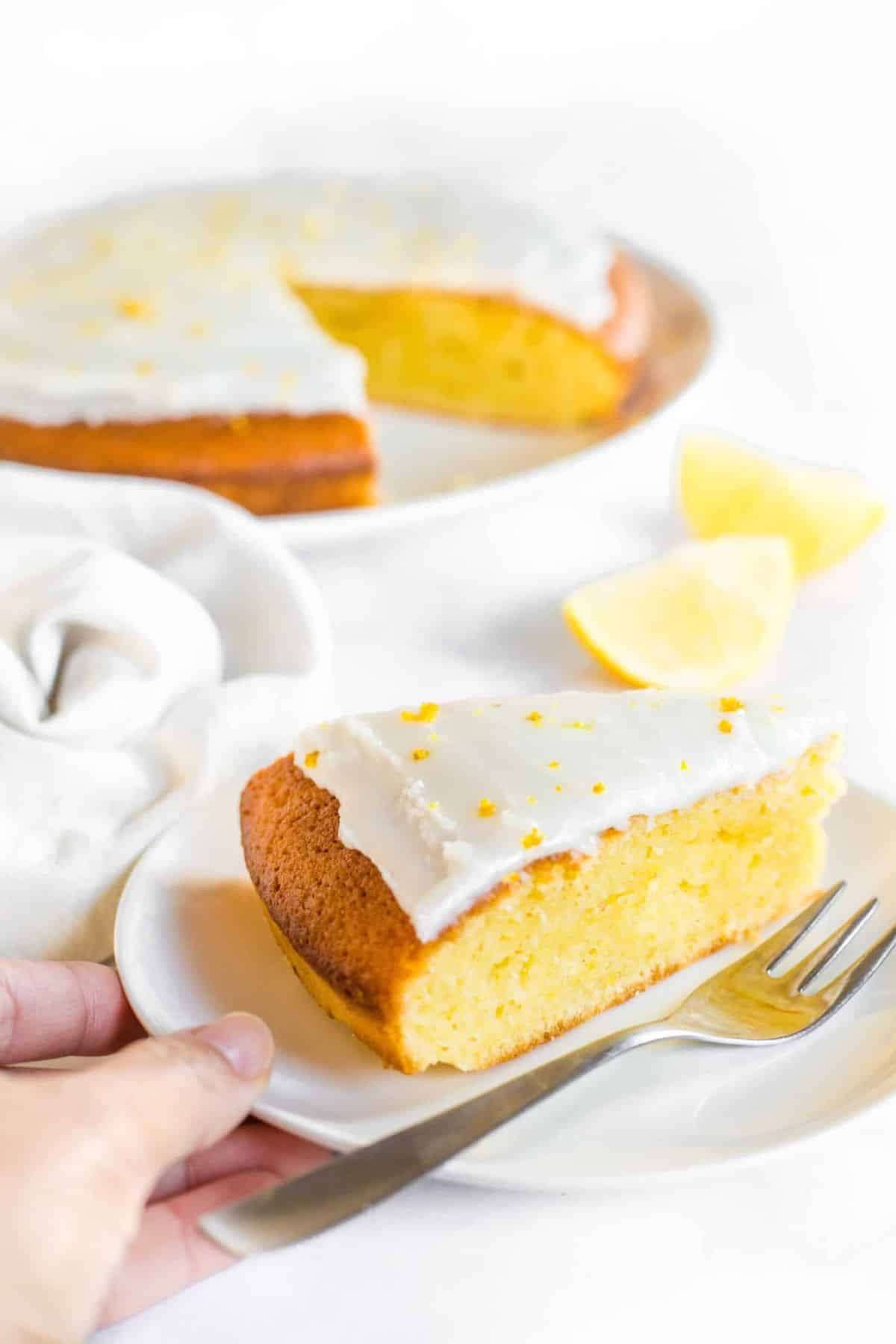 Gluten-Free Lemon Olive Oil Cake (Dairy-Free) Holding a plate with a slice of lemon olive oil cake.