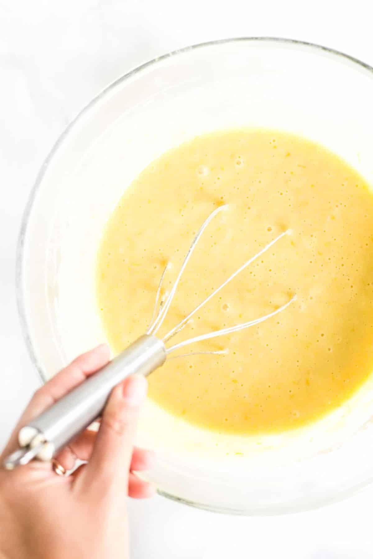Gluten-Free Dairy Free Olive Oil Cake (Dairy-Free) Whisking yellow liquid mixture in glass bowl.