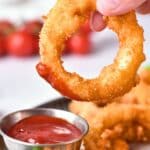 Dipping an onion ring into chili sauce.