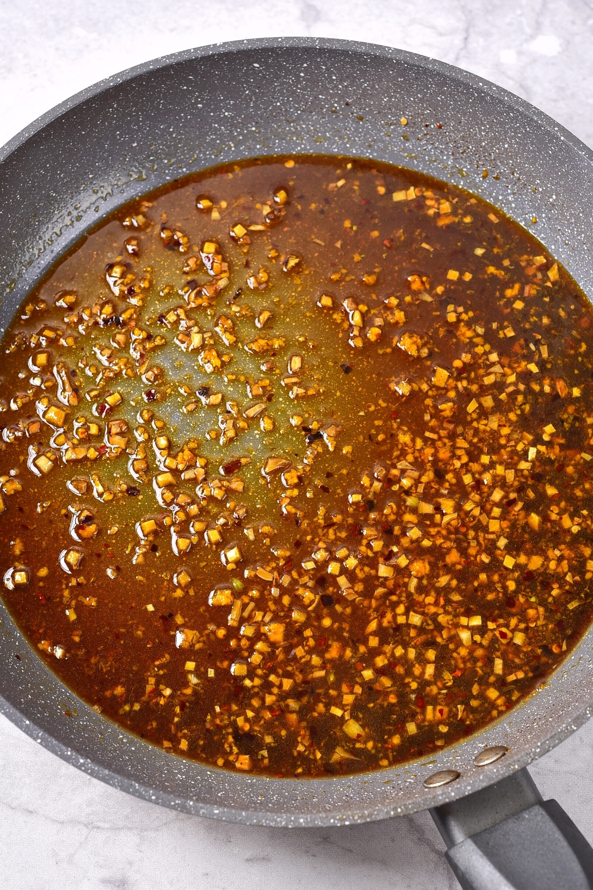 Easy Gluten-Free Orange Chicken (Dairy-Free) Preparing gluten-free orange chicken sauce in skillet.