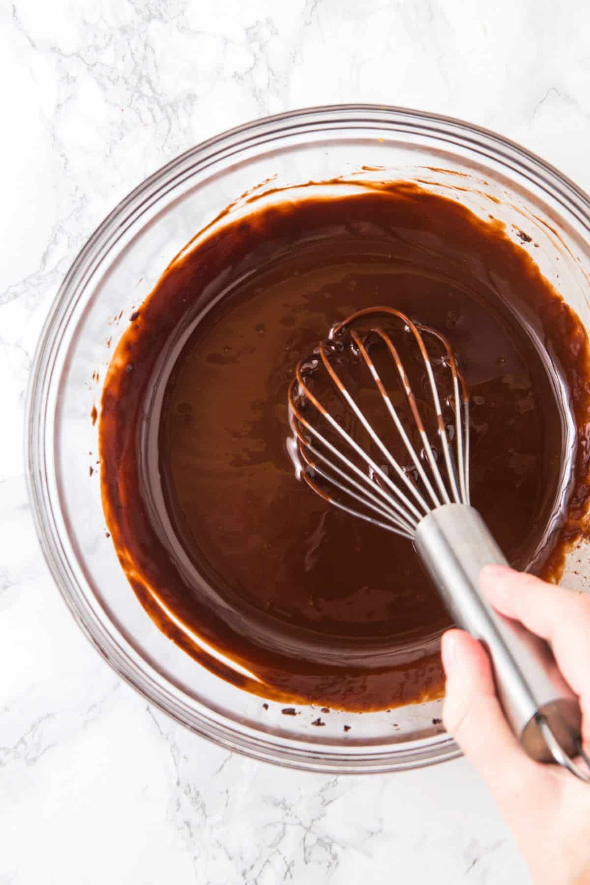 Whisking chocolate mixture in glass bowl.