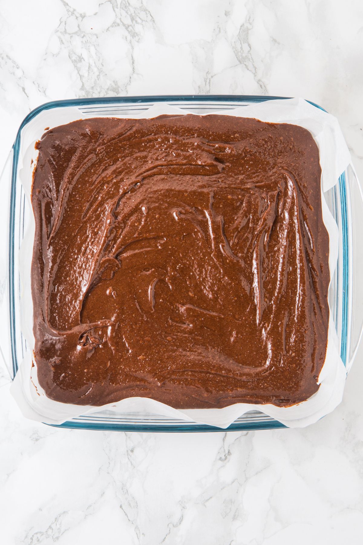 Brownie batter in parchment-lined baking pan.