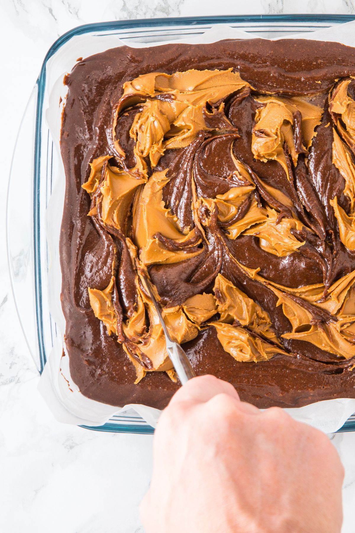 Using a knife to swirl peanut butter into brownie batter