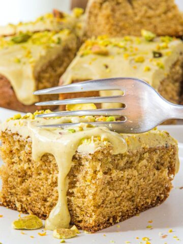 Fork cutting into a slice of pistachio cake